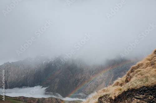 Rainbow in the mountains, peaks in the clouds