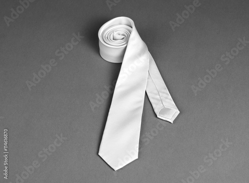 Beige necktie on gray background, roll of necktie on gray backgr