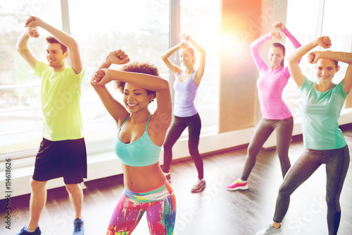 group of smiling people dancing in gym or studio photo