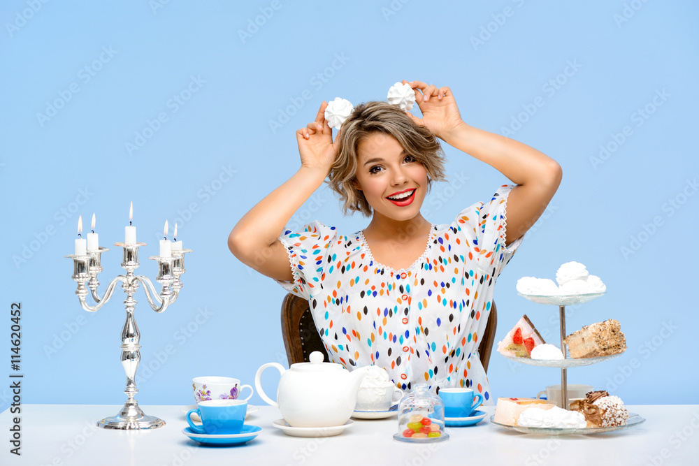 Portrait of young beautiful girl with sweets over blue background. Portrait of young beautiful girl with sweets over blue background.