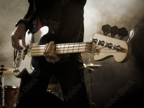 Rock band performs on stage. Bassist in the foreground. Close-up.