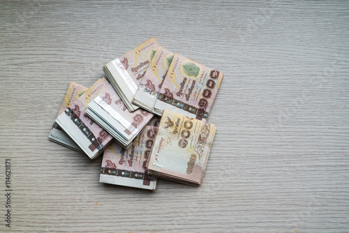 Stack of thousand bath Thai money on wooden table with copy space