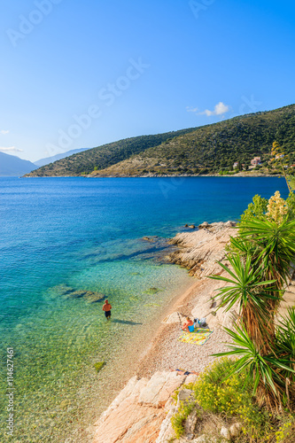 Unidentified couple of people relaxing on beach on coast of Kefalonia island in Agia Efimia, Greece