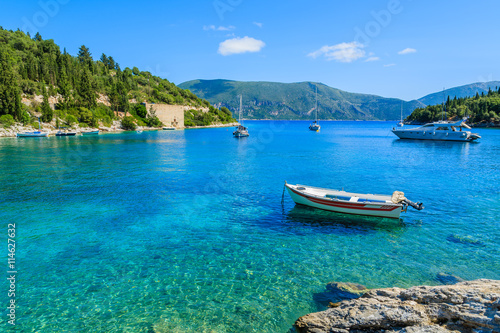 Fishing boat and yacht on turquoise sea in bay near Fiskardo village, Kefalonia island, Greece