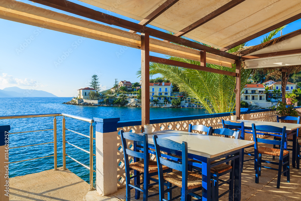 Fototapeta premium Blue chairs with tables in traditional Greek tavern in Fiskardo port, Kefalonia island, Greece