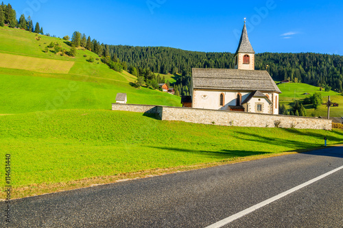 Scenic road and church on green meadow in South Tyrol, Dolomites Mountains, Italy photo