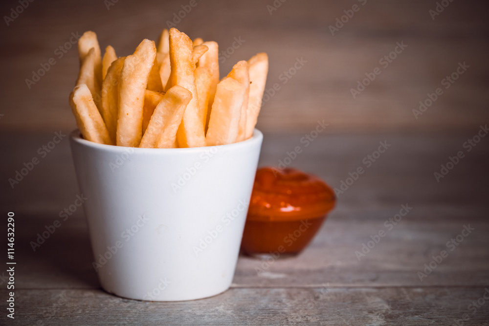 Toned photo. Color tone tuned. French fries on wooden background Toned photo. Color tone tuned. French fries on wooden background
