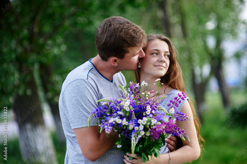 couple in love with bouquet are embracing in park