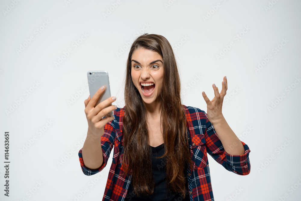 Young angry girl holding her phone in hand Young angry girl holding her phone in hand