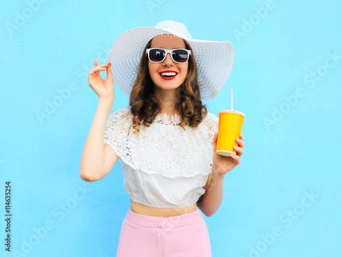 Fashion pretty smiling woman in straw hat with cup fruit juice o