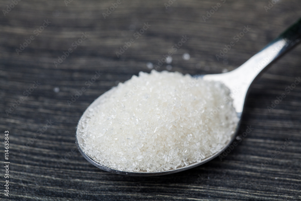 Close-up of granulated sugar in spoon and sugar pile. Close-up of granulated sugar in spoon and sugar pile.