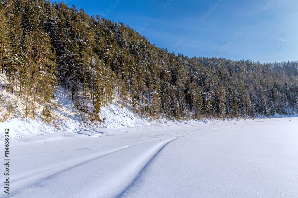 Snowmobile track on frozen mountain river Snowmobile track on frozen mountain river