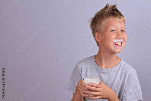 Happy smiling young boy with mustache from yogurt (milk, mustache). Dairy products concept