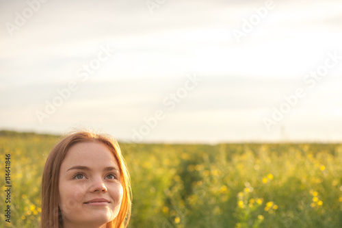woman with open arms in the green rapeseed field at the morning.
