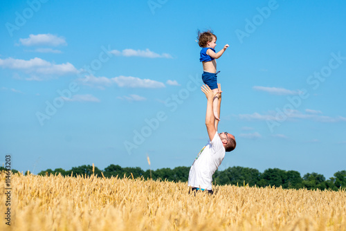 father tosses child in a wheat field