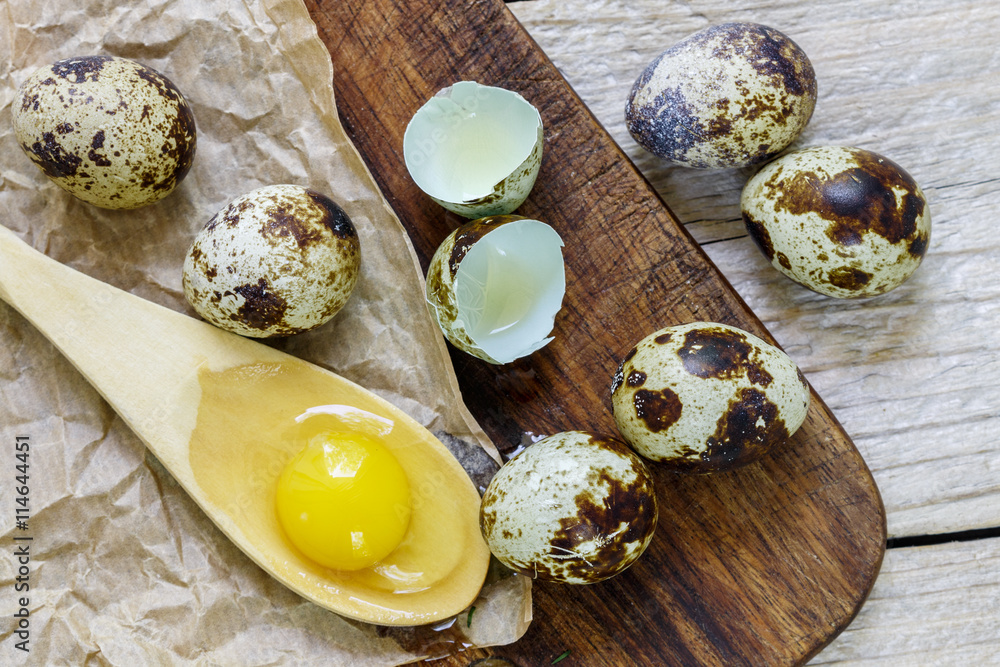 Yolk of quail eggs in a wooden spoon and quail eggs on the table Yolk of quail eggs in a wooden spoon and quail eggs on the table