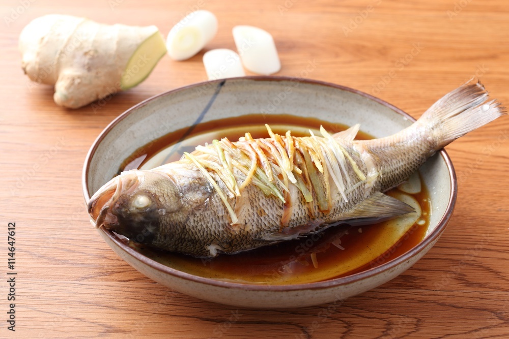 Steamed fried whole fish on traditional chinese plate with ginger Steamed fried whole fish on traditional chinese plate with ginger