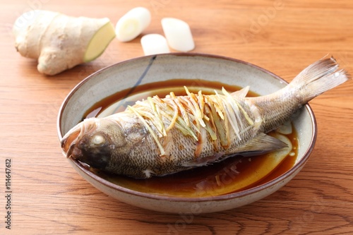Steamed fried whole fish on traditional chinese plate with ginger