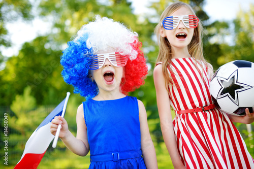 Two funny little sisters supporting and cheering their national football team