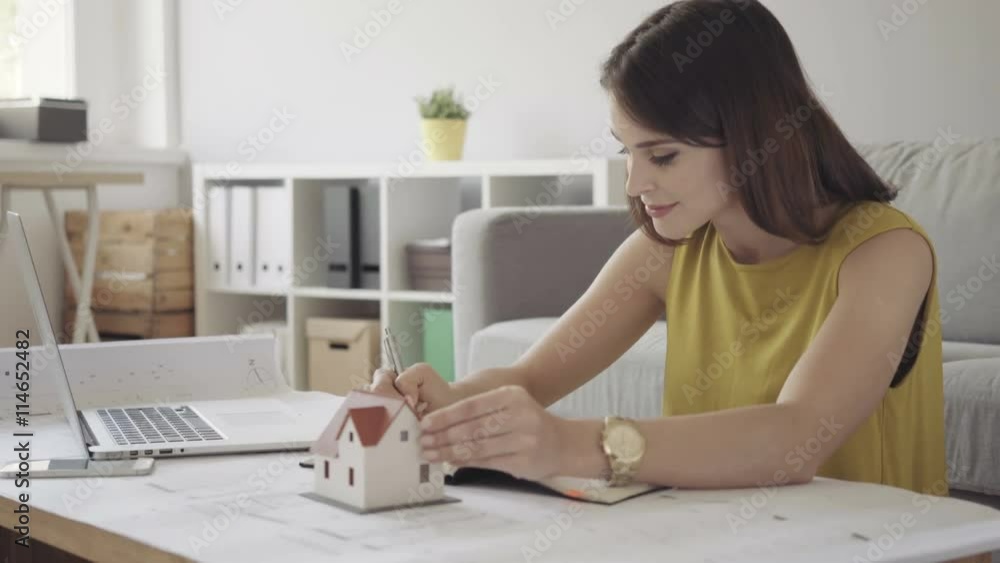Female architect working from home over some bluerprints Female architect working from home over some bluerprints