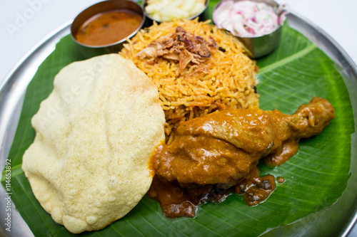 Indian meal with curry chiken and plain rice on banana leaf tray photo