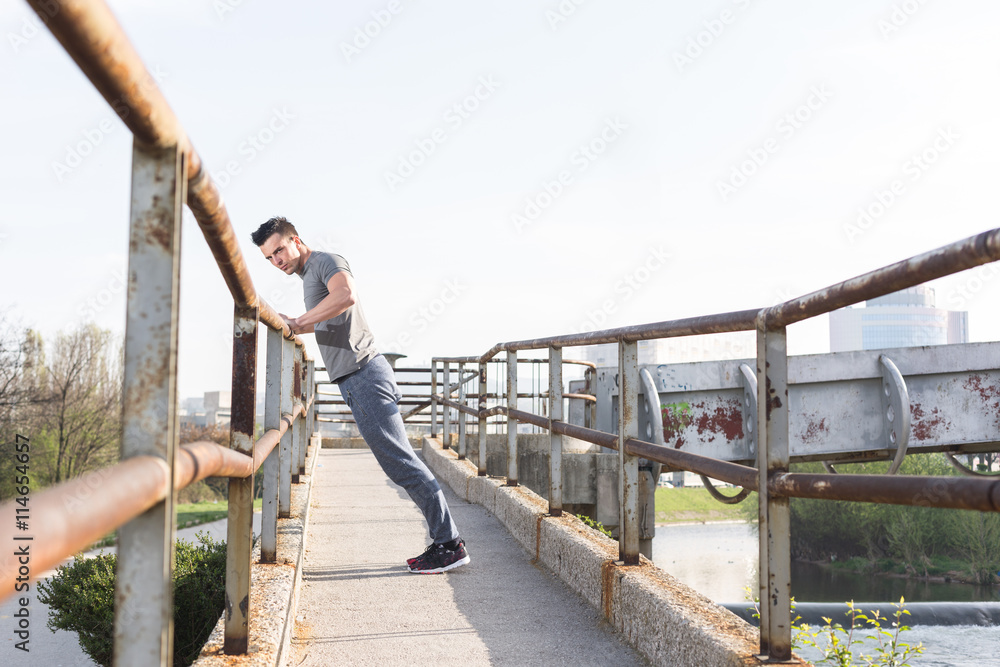 portrait of young sportsman stopped to rest near the iron fence portrait of young sportsman stopped to rest near the iron fence