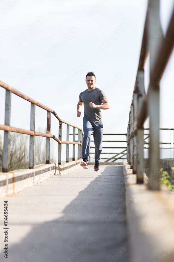 Full length portrait of handsome runner jogging fast down the br