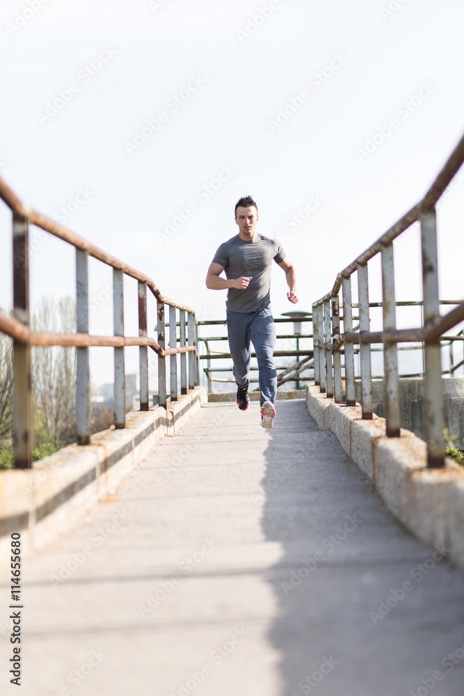 Full length portrait of handsome runner jogging fast down the br