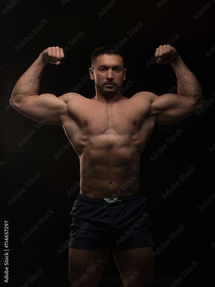 handsome muscular bodybuilder posing on a black background