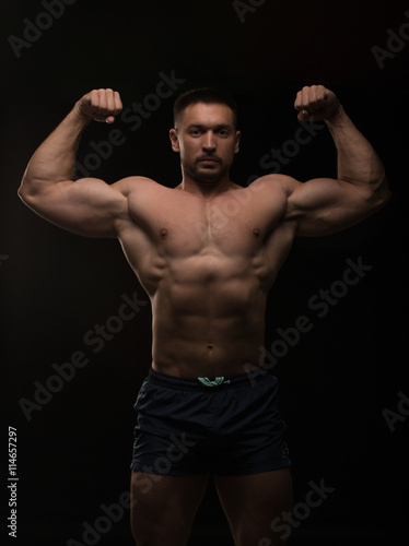 handsome muscular bodybuilder posing on a black background