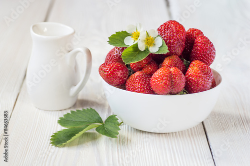 Appetizing strawberry in the bowl. White rustic table