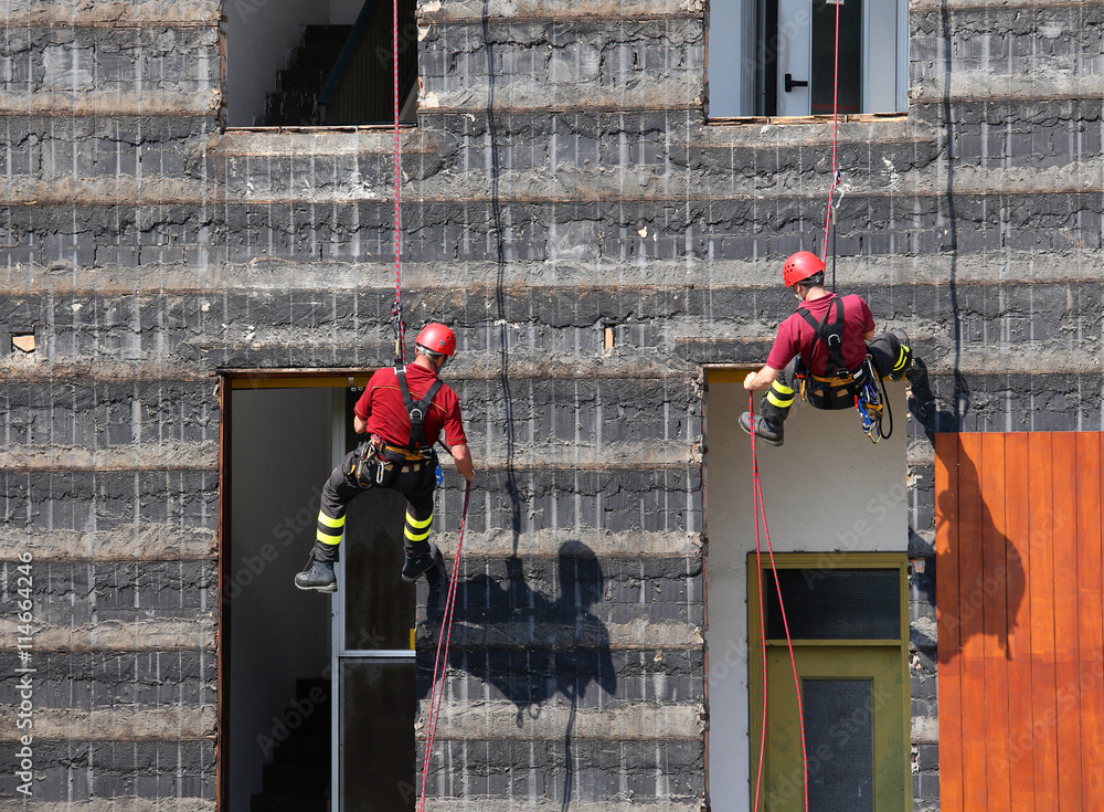 Fototapeta premium climbers of firefighters climbing a wall of a house during the f