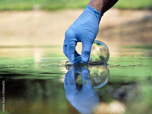 Water sample. Hand in glove collects water to explore. Concept - water purity analysis, environment, ecology. Water testing for infections, permission to swim 