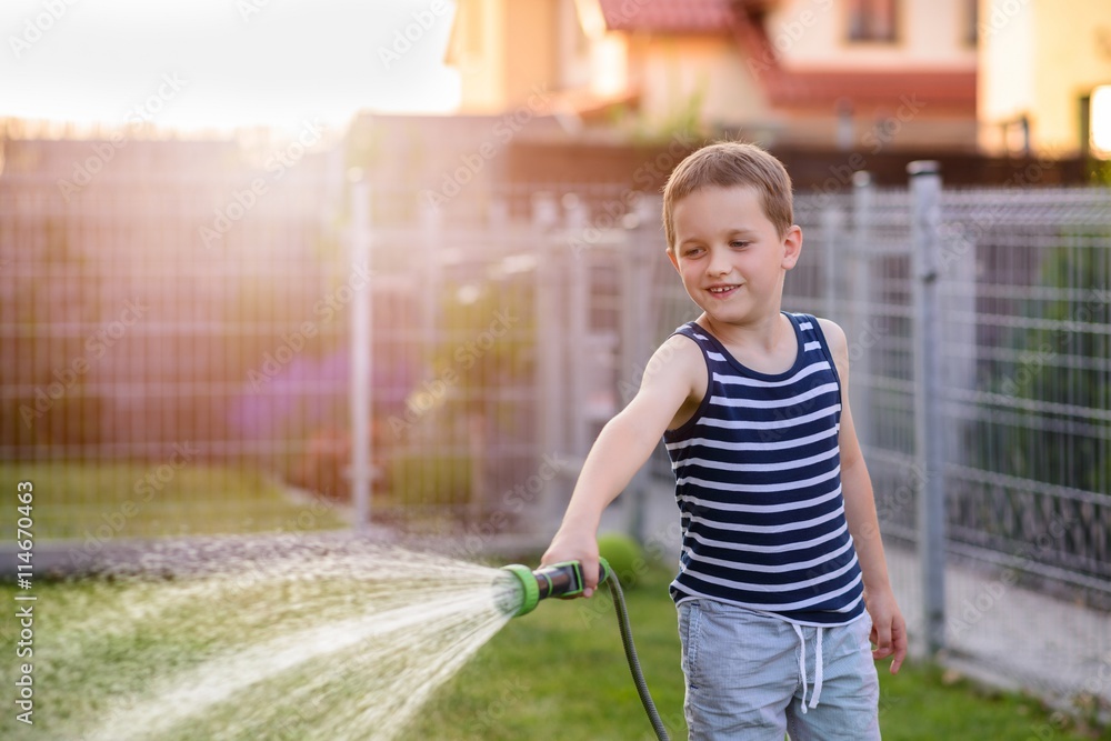 Fototapeta premium Little boy child watering grass in garden.