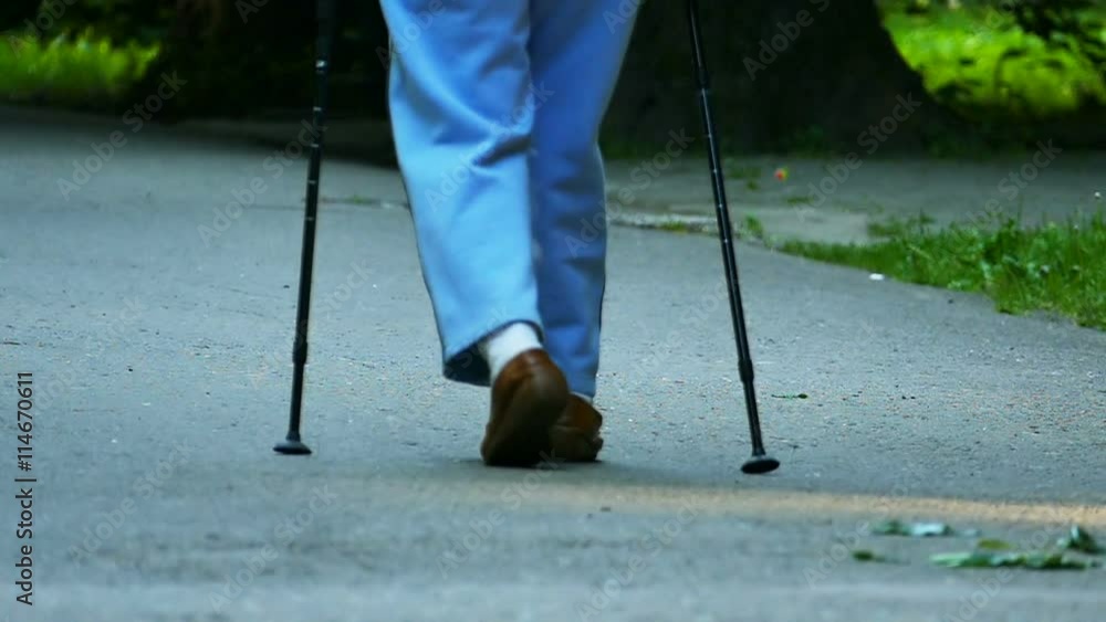 Slow motion. Old age woman with sticks for walking go in park. Slow motion. Old age woman with sticks for walking go in park.