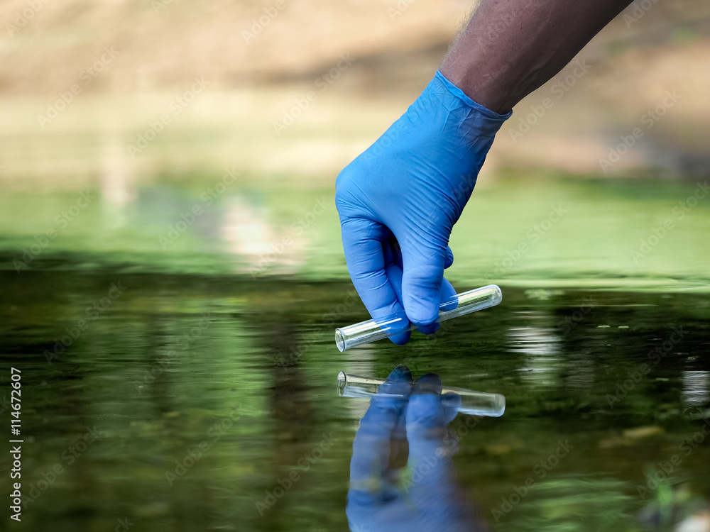 Water sample. Hand in glove collects water in a test tube. Concept