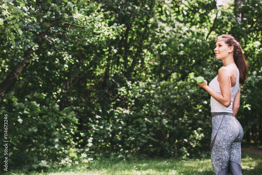 Woman doing exercises with dumbbells outdoors. Woman doing exercises with dumbbells outdoors.