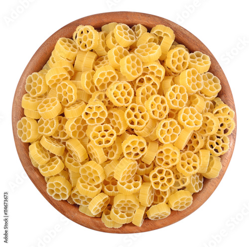 Uncooked italian pasta rotelle in a wooden bowl on a white