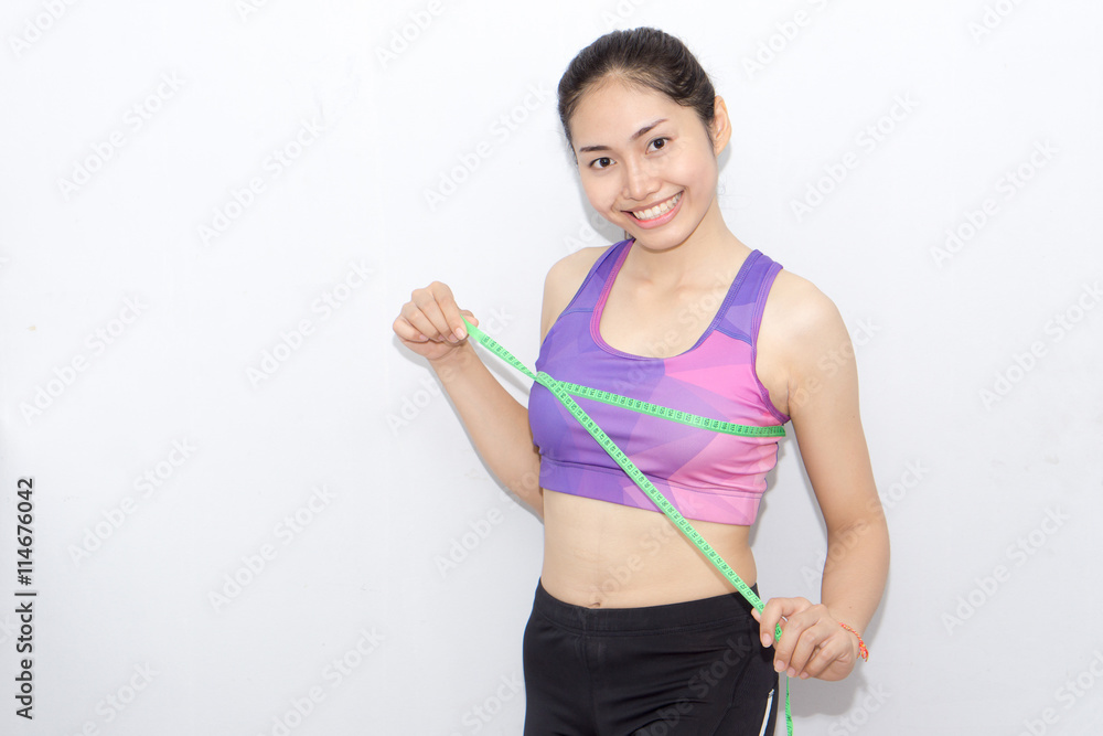 Woman in sport bra measuring her body with tape isolated on whit Woman in sport bra measuring her body with tape isolated on whit