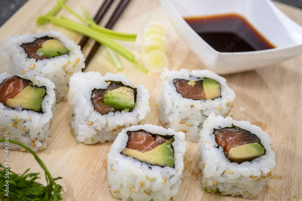 Sushi salmon rolls on cutting board with soy sauce, soy sprouts, onion grass and coriander Sushi salmon rolls on cutting board with soy sauce, soy sprouts, onion grass and coriander