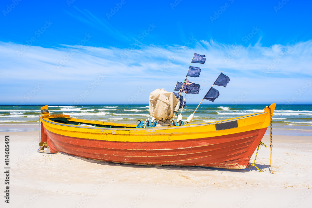 Colorful fishing boat on sandy Baltic Sea beach, Poland