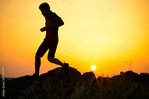 Young Sportsman Running on the Rocky Mountain Trail at Sunset. Active Lifestyle
