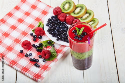 Berry smoothie.Fresh summer cocktail.Blueberry,raspberry,kiwi.Vitamin A. Vitamin C.Checkered napkin.On white wooden table with ingredients.Healthy lifestyle.Diet and weight loss concept.Top view