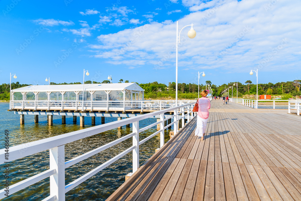 Fototapeta premium Unidentified woman wearing stylish dress walking on Jurata molo on Hel peninsula, Baltic Sea, Poland