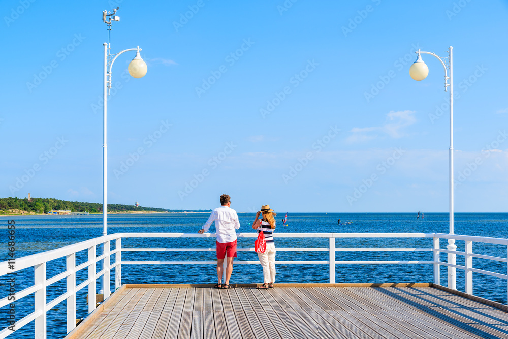 Fototapeta premium Unidentified couple of people standing on pier in Jurata town on Hel peninsula, Baltic Sea, Poland