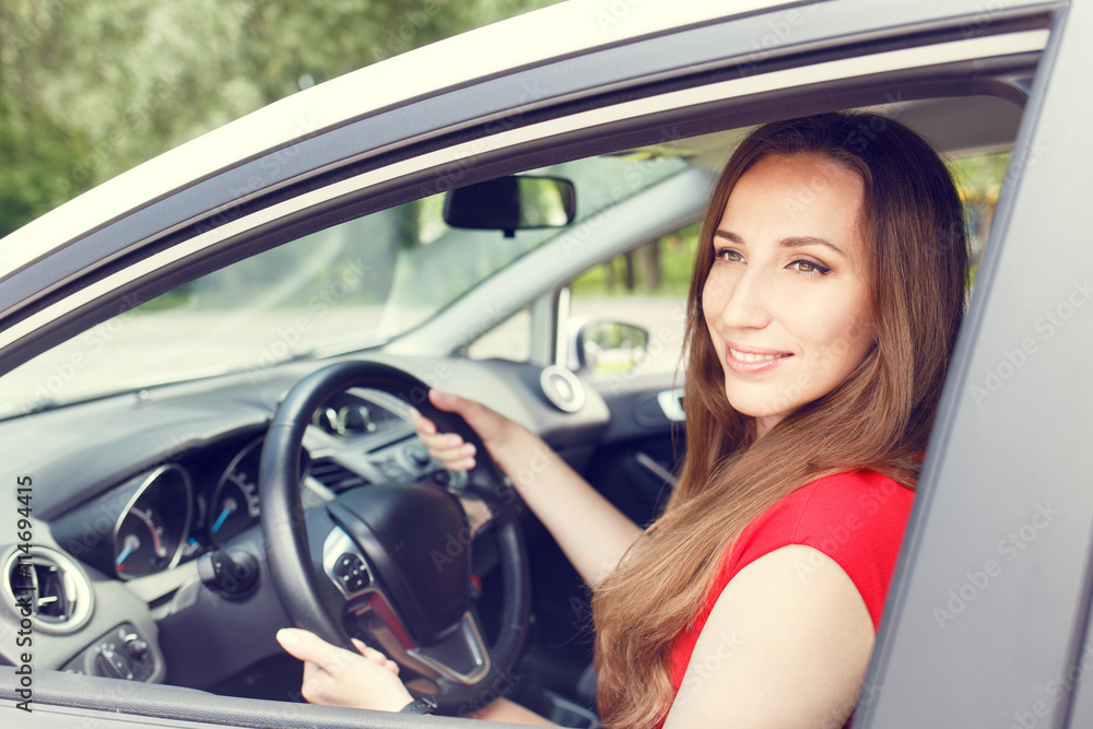Young happy woman driving a new or rented car