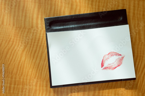 
Sexy girl Red lips kiss on blank white note paper on bed stand table in the morning light. 
romantic message from couple.  photo