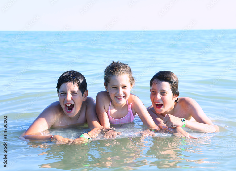 three young brothers playing in the water of the sea three young brothers playing in the water of the sea