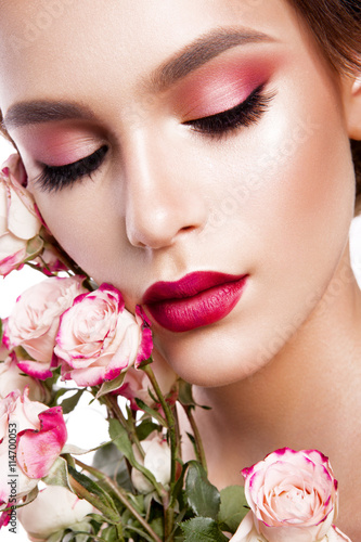 Portrait of young beautiful woman with stylish make-up and colorful roses around her face