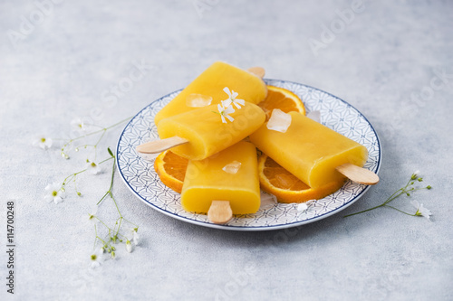 Dish with homemade orange popsicles photo